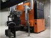 In einem Heizungsraum steht eine Holzhackschnitzel- / Restholzheizung des Produkttyps UTSD E-Clean inklusive eines elektronischen Partikelabscheiders und der Sauganlage von Schmid.