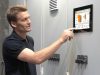 Mann bedient Steuerung PersonalTouch visio auf digitalem Display an einem elektronischen Schaltschrank, um die Holzheizung zu bedienen.